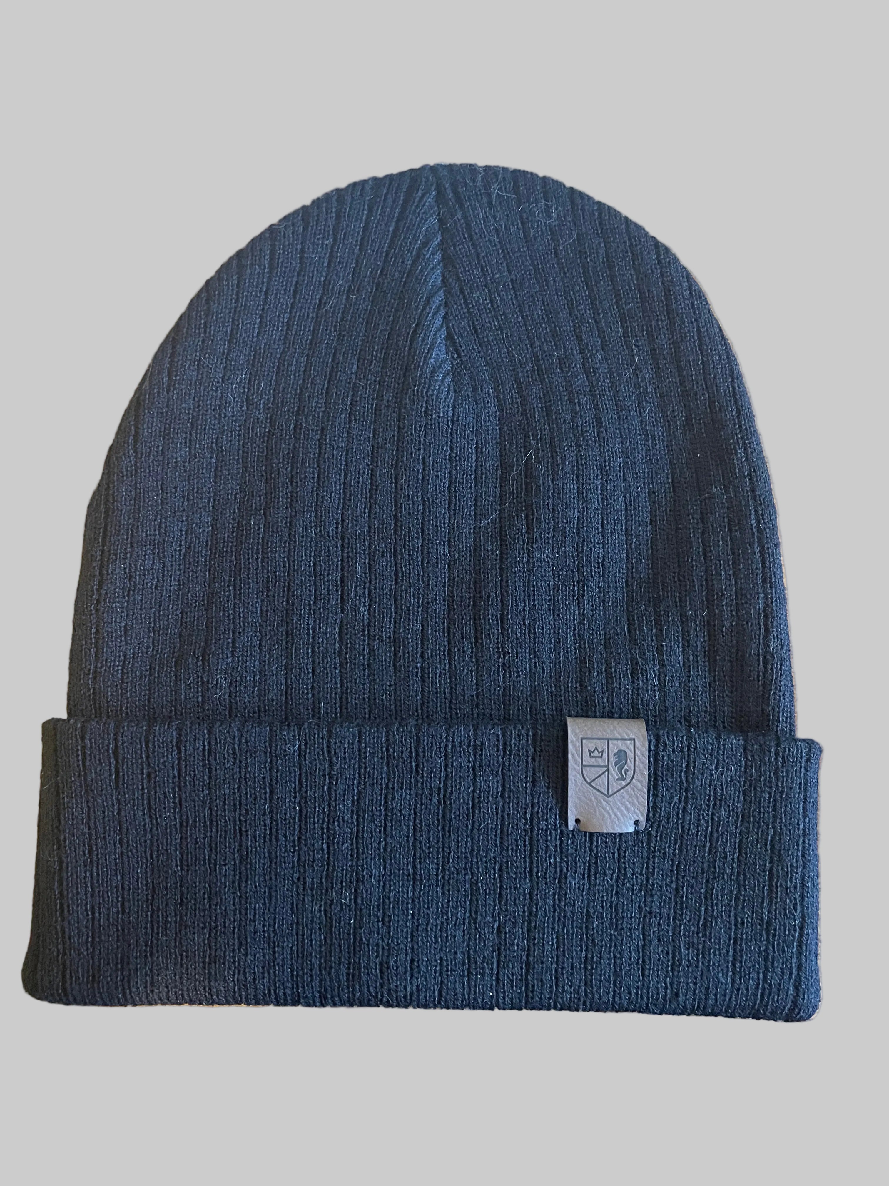 Blue knit beanie with a brand label on a wooden surface