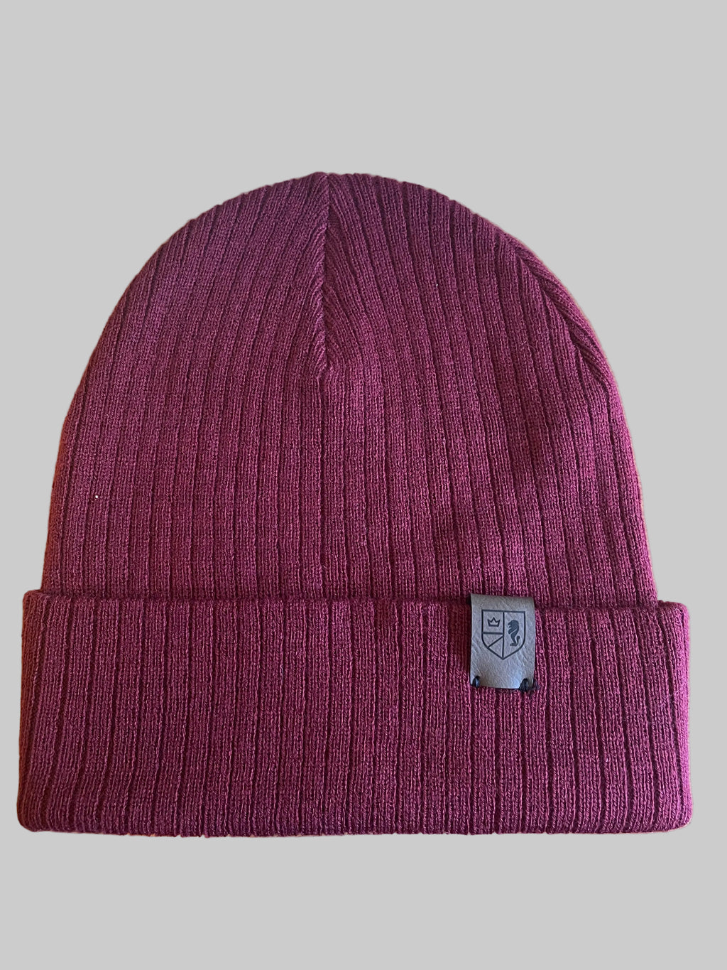 Maroon beanie with a brand logo on a wooden surface next to a keyboard