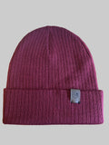 Maroon beanie with a brand logo on a wooden surface next to a keyboard