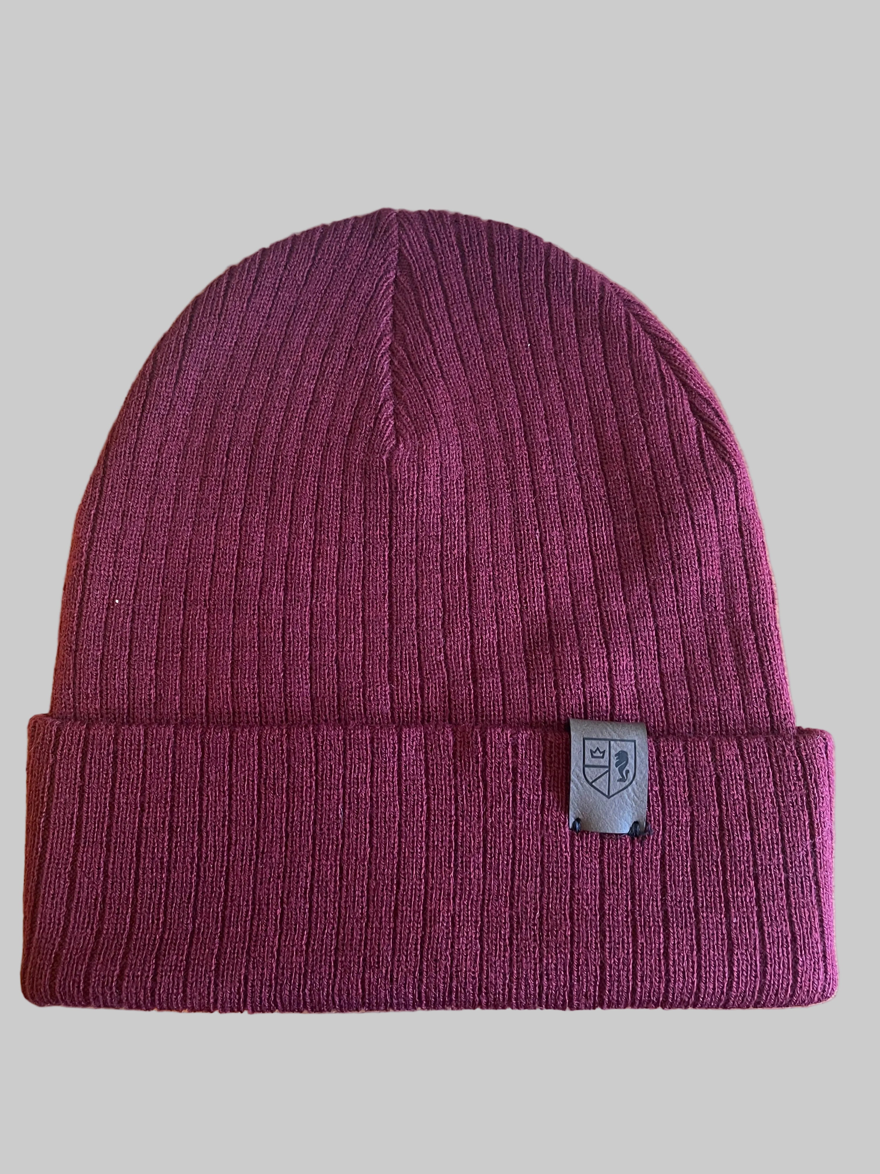 Maroon beanie with a brand logo on a wooden surface next to a keyboard